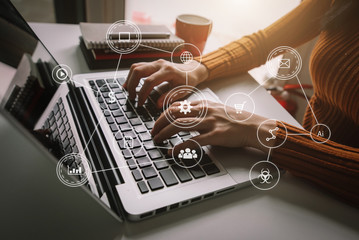 Hands typing on a laptop surrounded by floating automation and business icons in warm light
